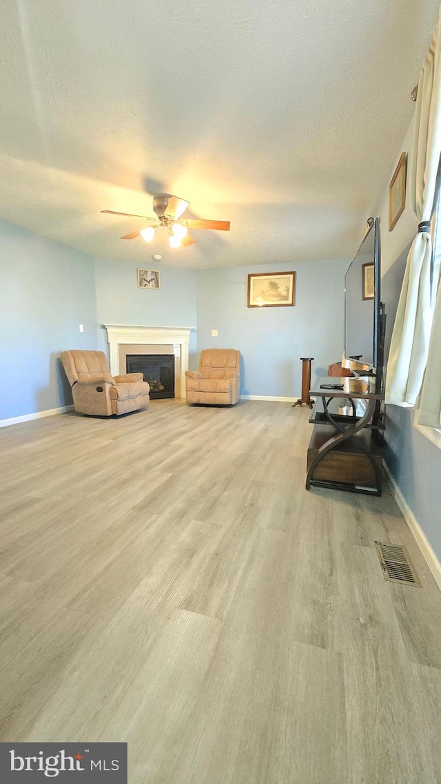 sitting room with ceiling fan, light hardwood / wood-style floors, and a textured ceiling