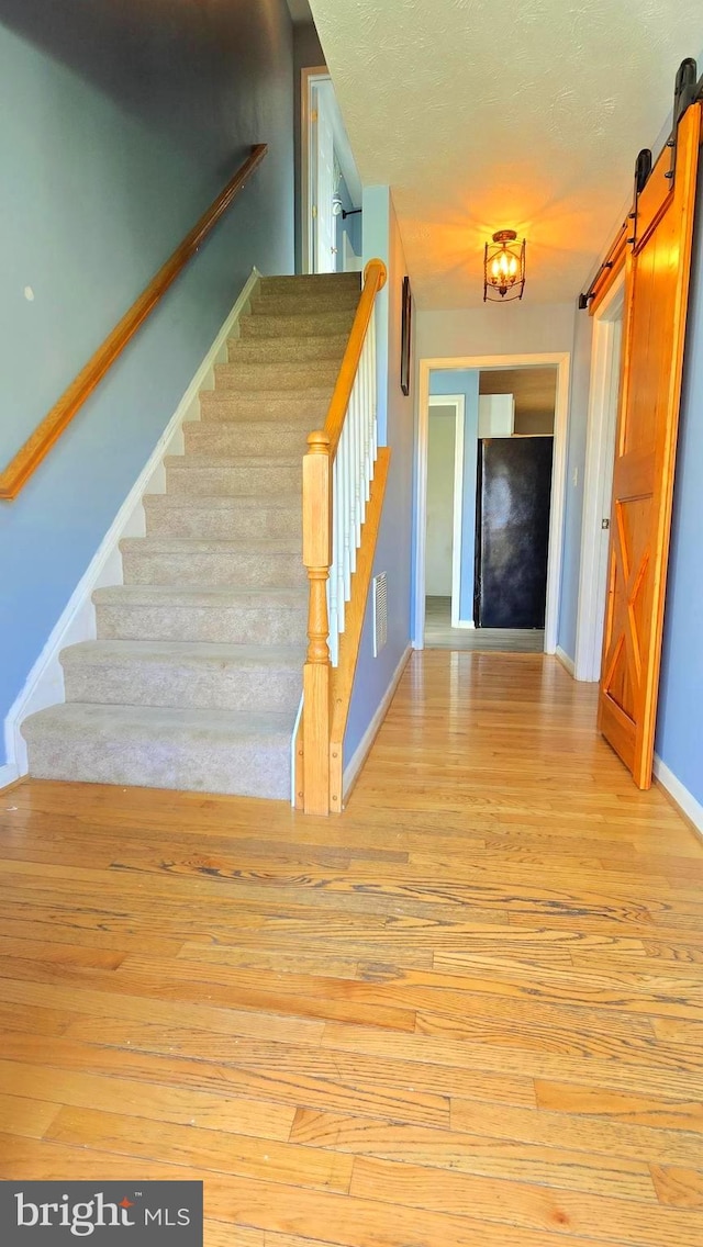 stairway featuring a barn door and hardwood / wood-style flooring