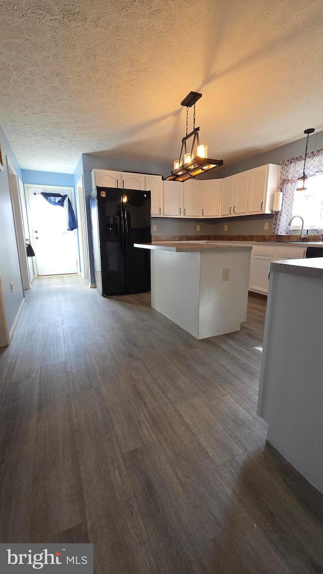 kitchen featuring black fridge with ice dispenser, dark hardwood / wood-style flooring, decorative light fixtures, and white cabinetry