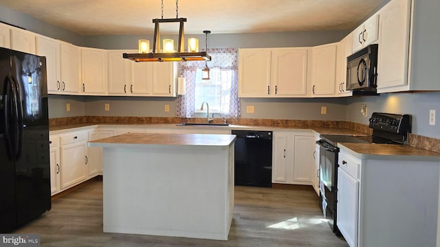 kitchen featuring sink, black appliances, decorative light fixtures, dark hardwood / wood-style floors, and a kitchen island