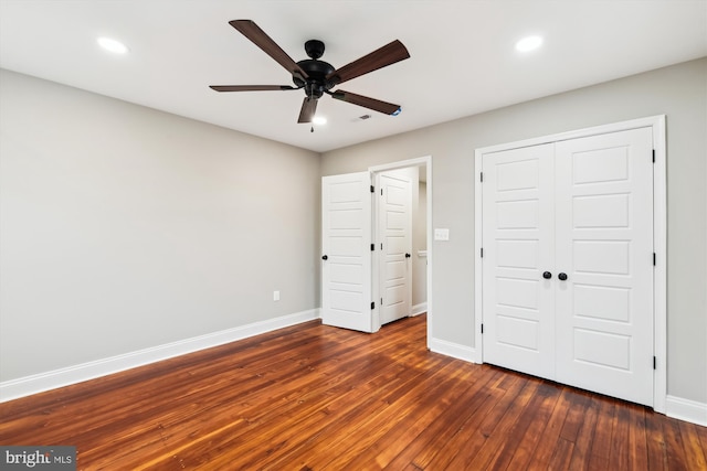 unfurnished bedroom with ceiling fan, dark wood-type flooring, and a closet