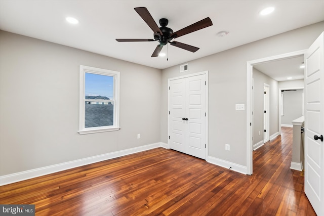 unfurnished bedroom with dark hardwood / wood-style floors, ceiling fan, and a closet