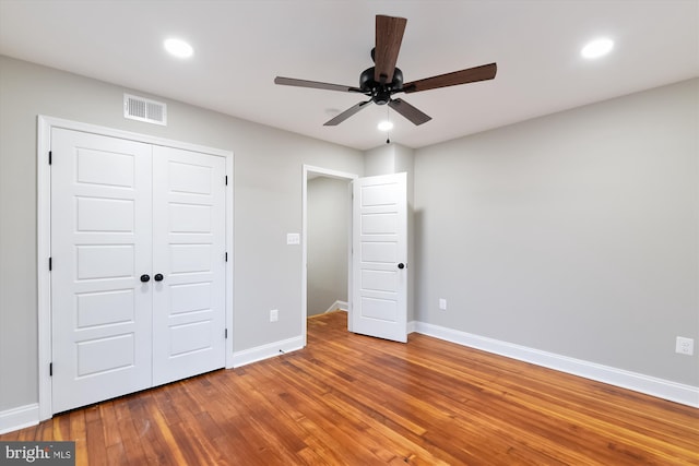 unfurnished bedroom with hardwood / wood-style floors, ceiling fan, and a closet