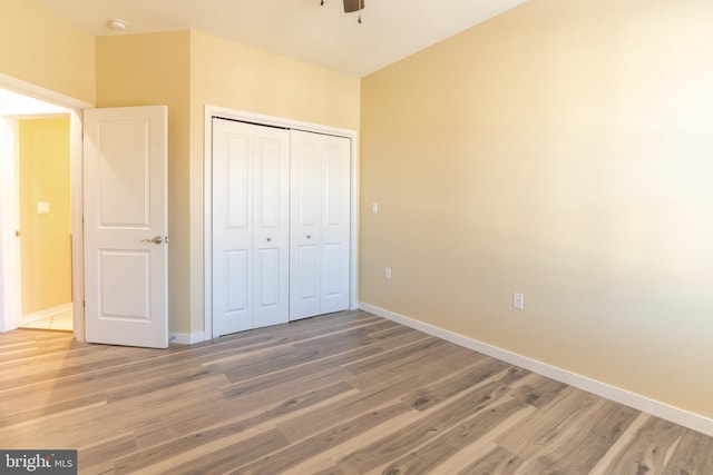 unfurnished bedroom with hardwood / wood-style floors, a closet, and ceiling fan