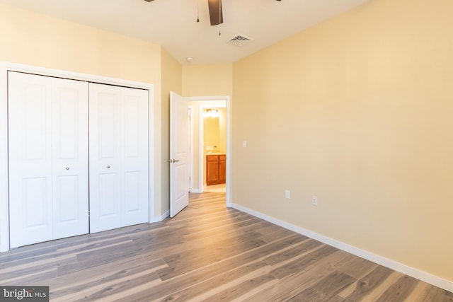 unfurnished bedroom featuring ceiling fan, a closet, and wood-type flooring