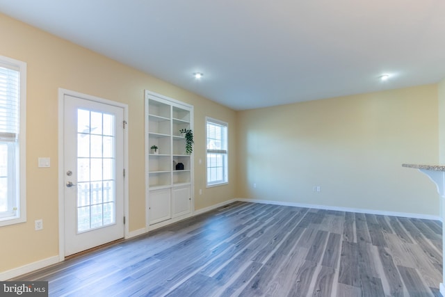 unfurnished living room featuring a wealth of natural light and wood-type flooring