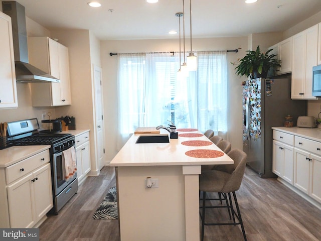 kitchen with a center island with sink, wall chimney range hood, sink, dark hardwood / wood-style floors, and stainless steel appliances