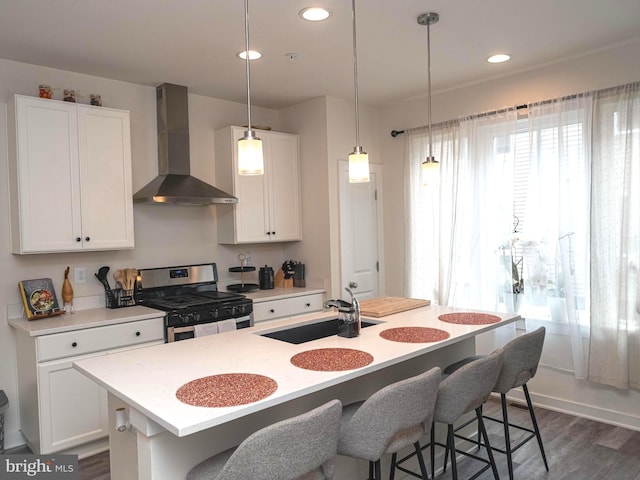 kitchen with a center island with sink, wall chimney exhaust hood, sink, and gas range