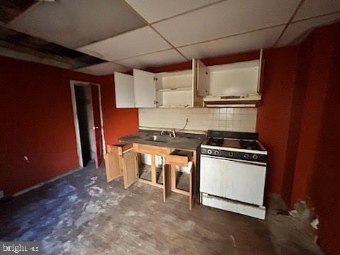 kitchen featuring white cabinets, a paneled ceiling, backsplash, and gas range gas stove