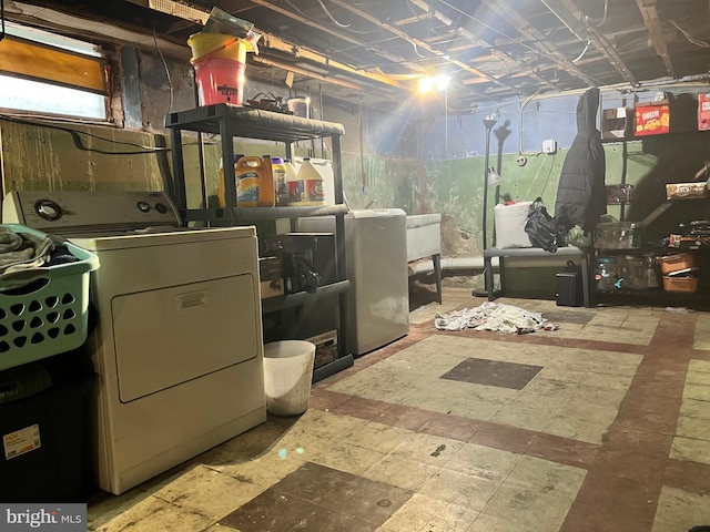 basement featuring washer and clothes dryer and stainless steel fridge