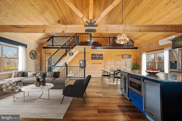 living room featuring plenty of natural light, wood walls, a chandelier, and lofted ceiling with beams