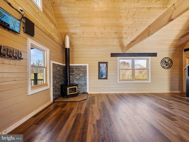 unfurnished living room featuring a wood stove, a wealth of natural light, wooden walls, and dark hardwood / wood-style floors