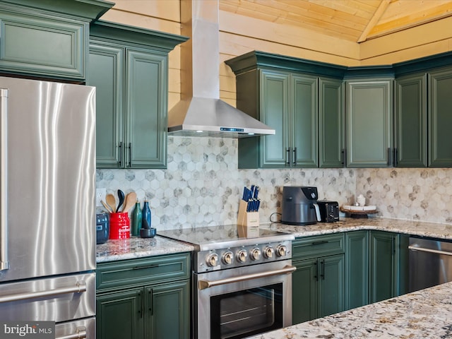 kitchen featuring lofted ceiling, stainless steel appliances, wall chimney range hood, and green cabinetry