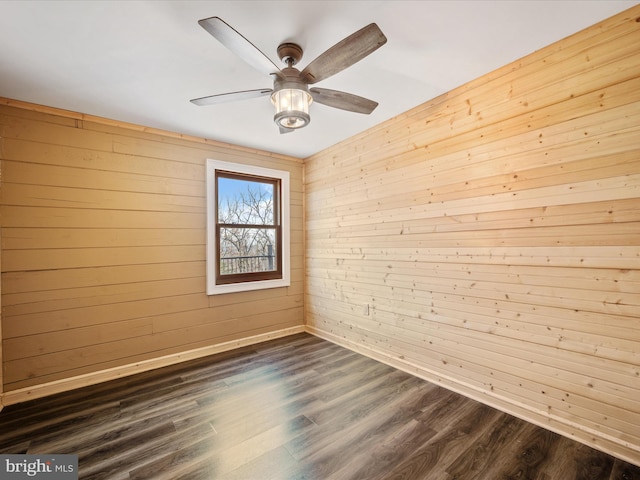 empty room featuring dark hardwood / wood-style floors, wood walls, and ceiling fan