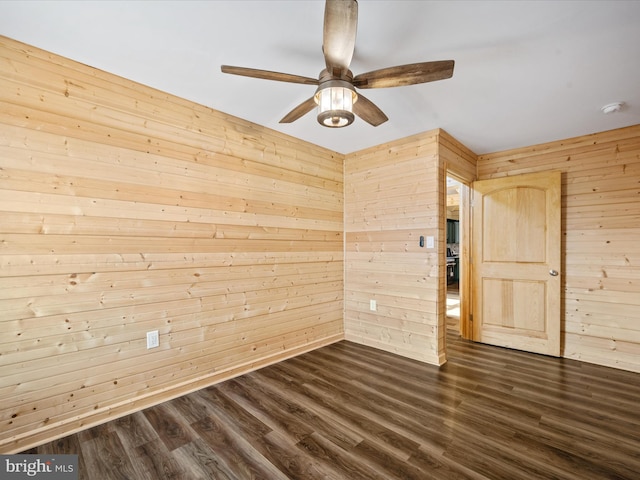 spare room featuring wood walls, dark hardwood / wood-style flooring, and ceiling fan