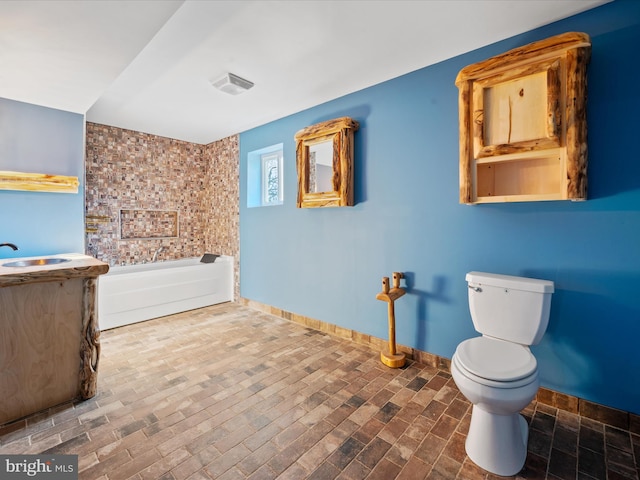 bathroom featuring vanity, toilet, and a tub