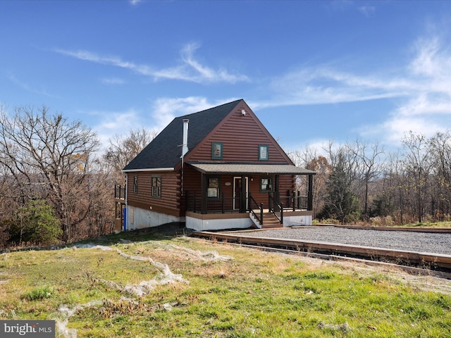 back of house with covered porch and a yard