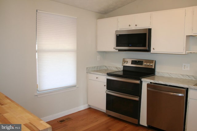 kitchen with white cabinetry, lofted ceiling, stainless steel appliances, and light hardwood / wood-style flooring