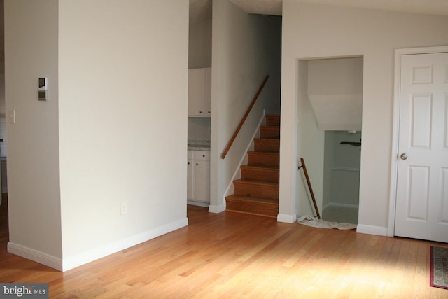 stairway featuring wood-type flooring and lofted ceiling