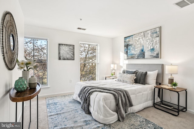 bedroom with light colored carpet and multiple windows