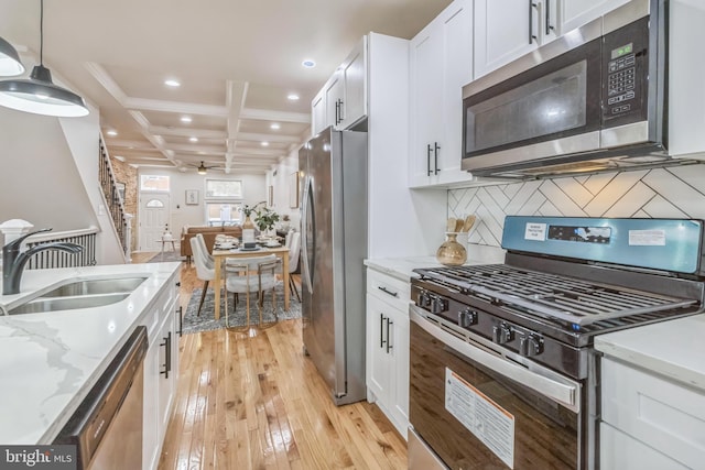 kitchen featuring appliances with stainless steel finishes, backsplash, decorative light fixtures, white cabinets, and light hardwood / wood-style floors