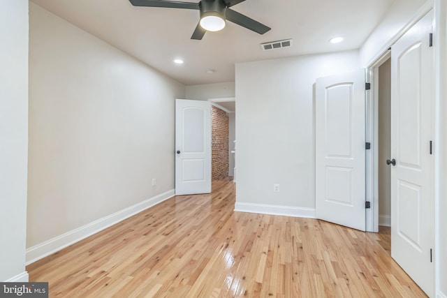 unfurnished bedroom with light hardwood / wood-style floors, ceiling fan, and brick wall