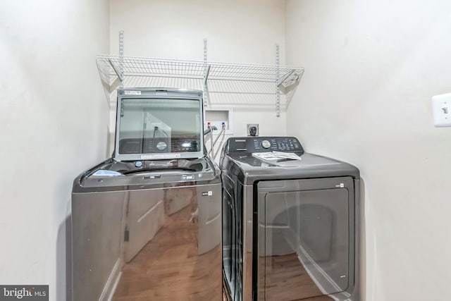 clothes washing area with hardwood / wood-style floors and separate washer and dryer