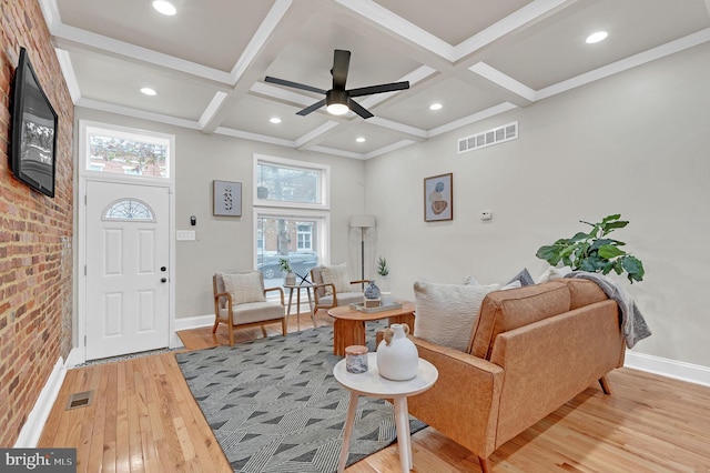 interior space featuring coffered ceiling, ceiling fan, beamed ceiling, light hardwood / wood-style floors, and brick wall