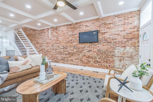 living room featuring beam ceiling, coffered ceiling, brick wall, crown molding, and wood-type flooring