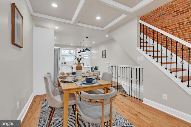 dining room with coffered ceiling, crown molding, light wood-type flooring, beamed ceiling, and brick wall