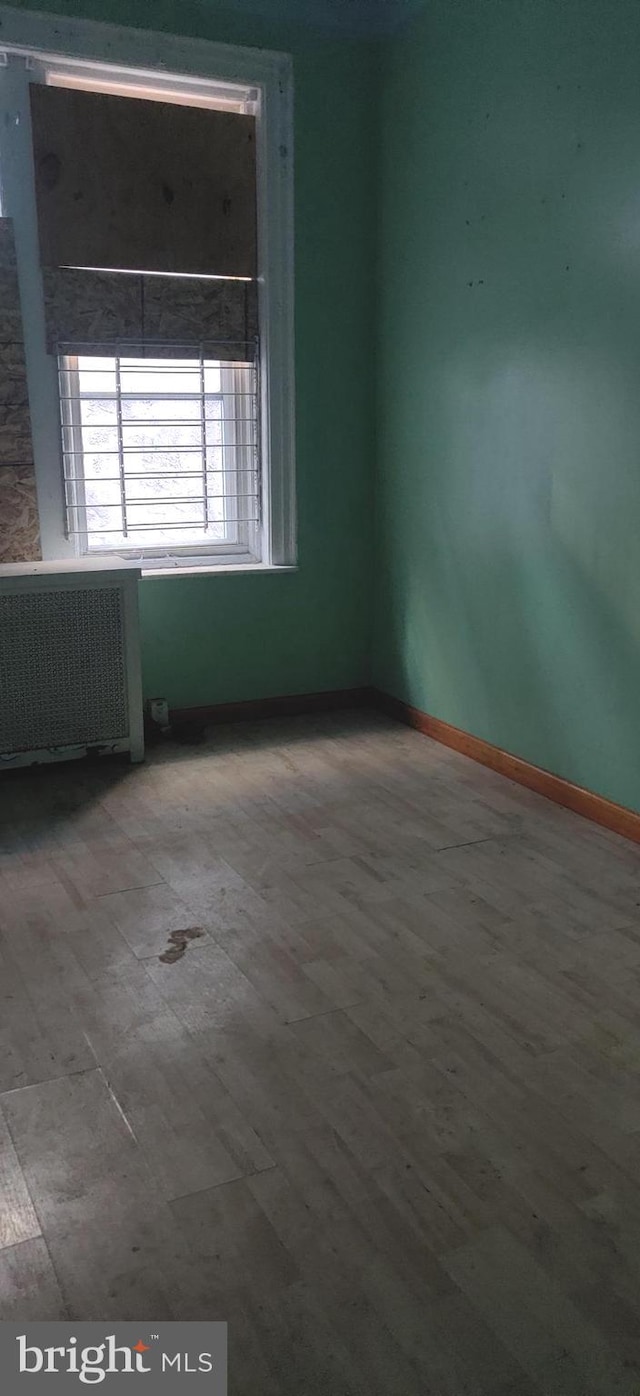 spare room featuring radiator and light hardwood / wood-style floors