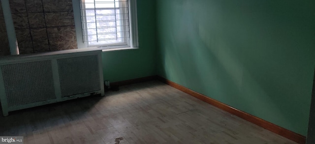 spare room featuring radiator heating unit and hardwood / wood-style flooring