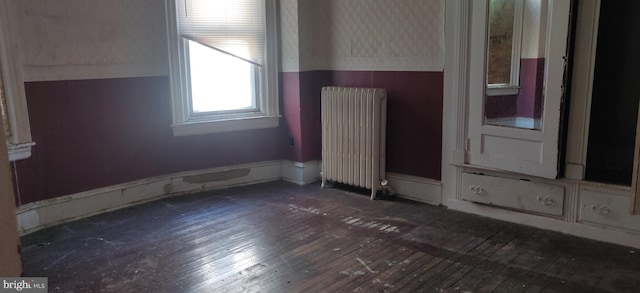 empty room featuring radiator and dark hardwood / wood-style flooring