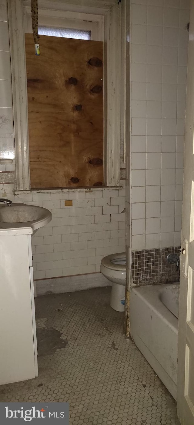 bathroom featuring tile patterned floors, a tub, vanity, and toilet