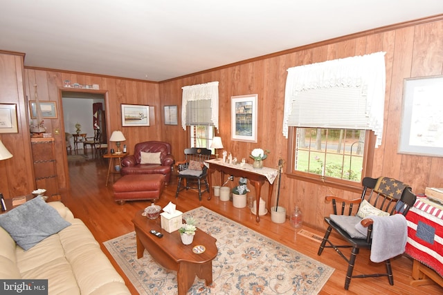 living room with hardwood / wood-style floors, ornamental molding, and wood walls