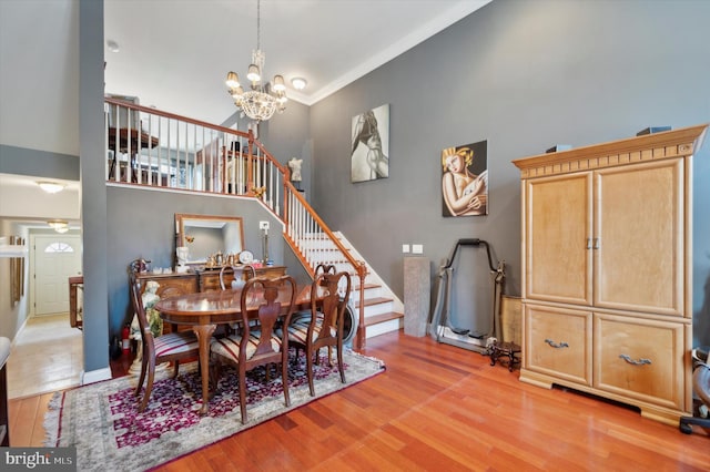 dining area with a chandelier, a towering ceiling, and light hardwood / wood-style flooring