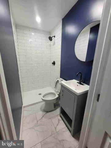 213 N Ramsey St, Philadelphia, PA 19139 - bathroom with marble finish floor, tiled shower, vanity, and toilet