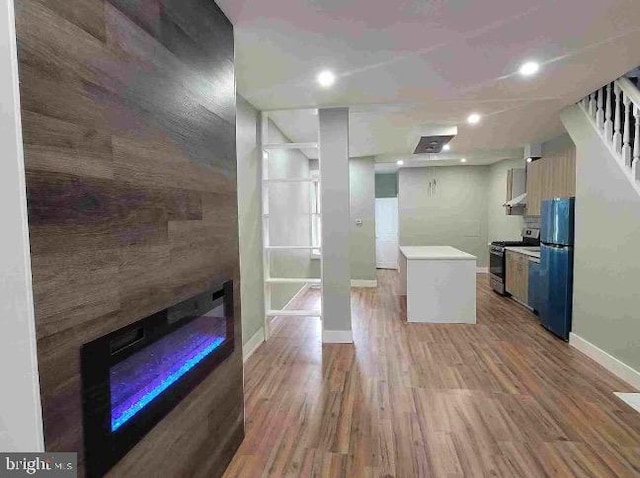 kitchen featuring wood finished floors, baseboards, light countertops, freestanding refrigerator, and stainless steel gas stove