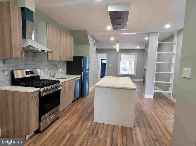 213 N Ramsey St, Philadelphia, PA 19139 - kitchen with stainless steel appliances, a kitchen island, a sink, wall chimney exhaust hood, and light wood finished floors