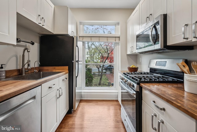 kitchen featuring wood counters, appliances with stainless steel finishes, light wood-type flooring, and white cabinets