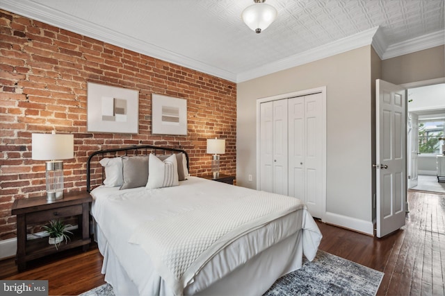 bedroom with crown molding, a closet, dark wood-type flooring, and brick wall