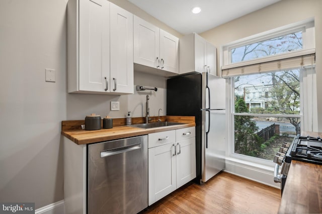 kitchen with butcher block countertops, white cabinetry, and stainless steel appliances