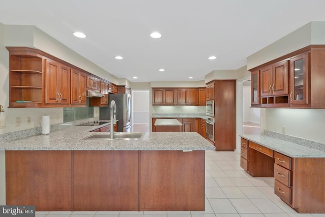 kitchen featuring kitchen peninsula, light stone counters, built in desk, and appliances with stainless steel finishes