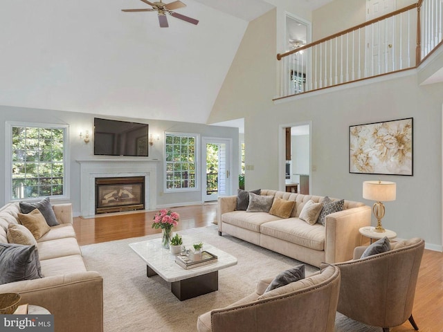 living room featuring light hardwood / wood-style floors, high vaulted ceiling, ceiling fan, and a healthy amount of sunlight