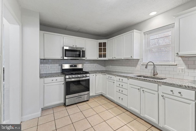 kitchen featuring sink, light tile patterned floors, tasteful backsplash, white cabinetry, and stainless steel appliances