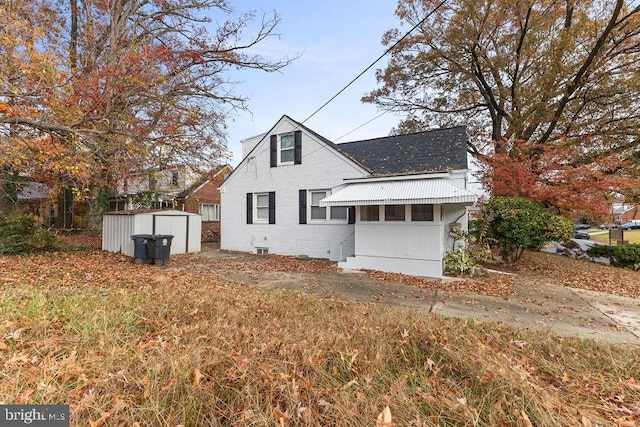 rear view of house featuring a storage shed