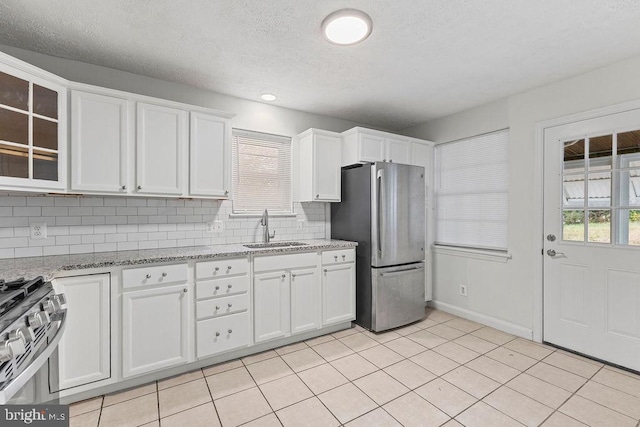 kitchen with light stone countertops, white cabinetry, sink, and stainless steel appliances