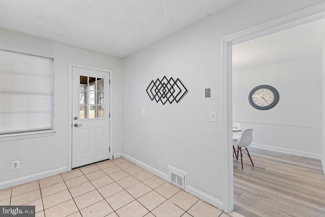 foyer entrance with a textured ceiling and light wood-type flooring