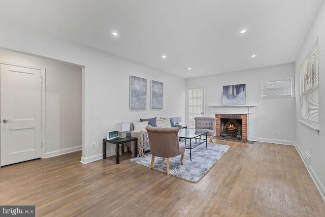 living room featuring a brick fireplace and light wood-type flooring