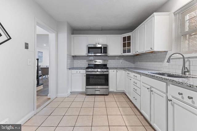 kitchen featuring decorative backsplash, light stone counters, stainless steel appliances, sink, and white cabinetry